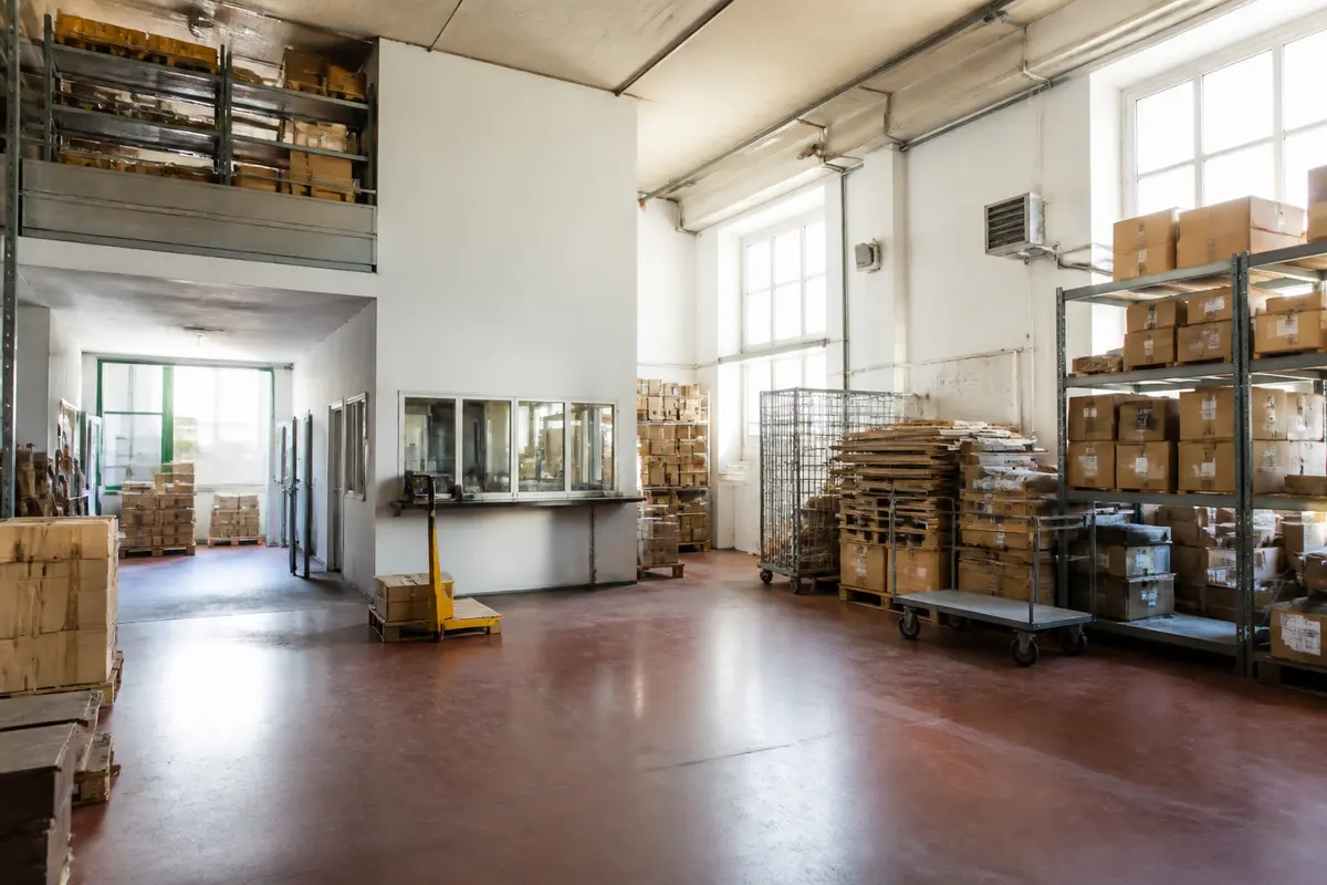 Interno di un magazzino con scatole su scaffali, evidenzia spazio magazzino in affitto.